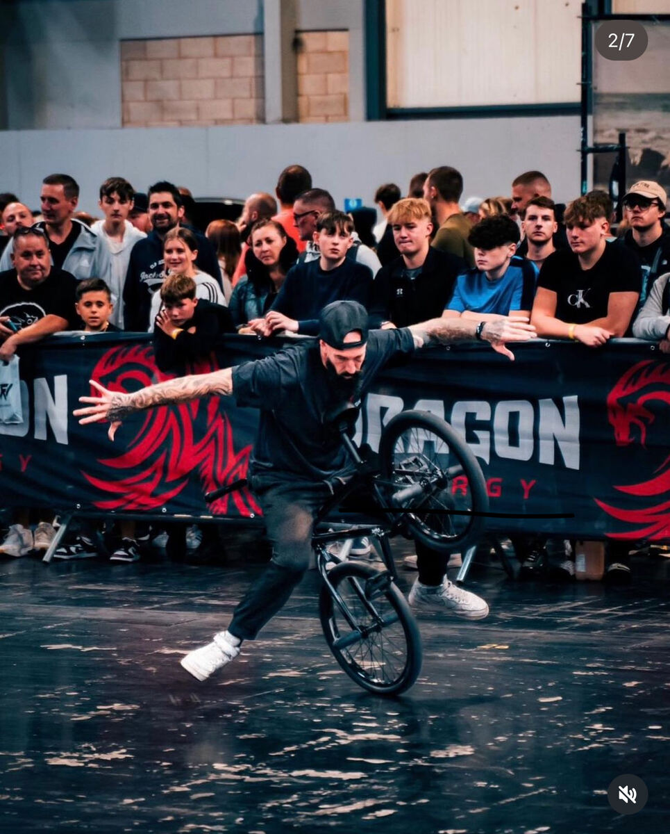 BMX rider performing tricks in front of Dragon Energy banners and a packed crowd