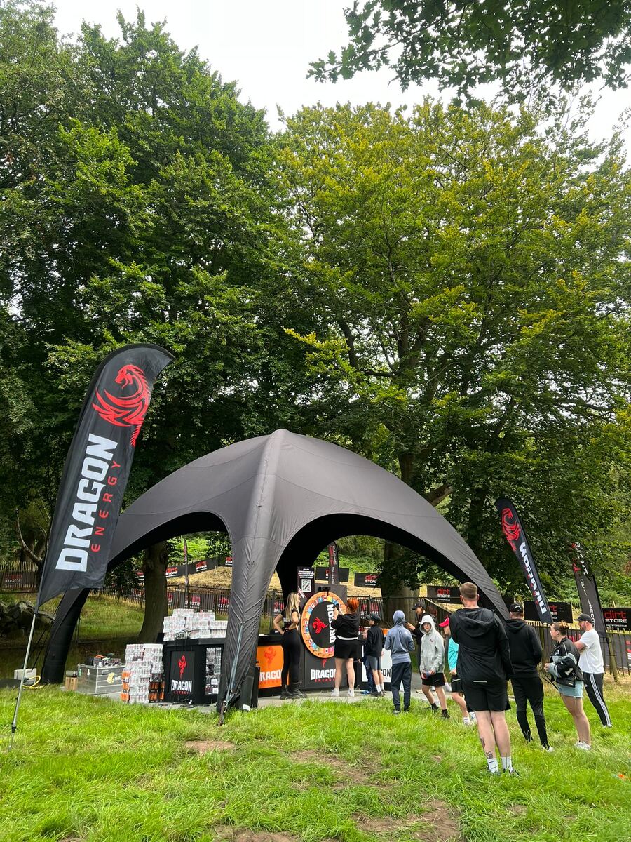 Dragon Energy branded activation tent and feather flags at an outdoor event
