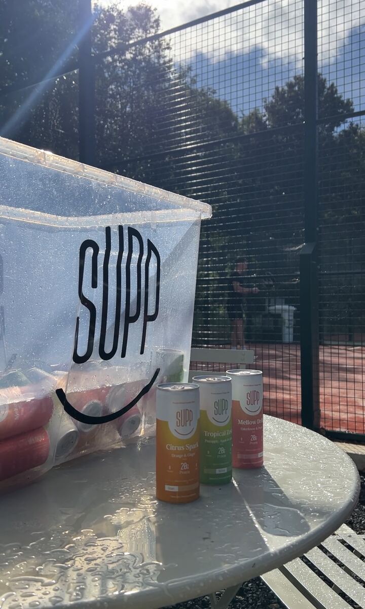 SUPP branded cooler with cans on outdoor table at the Padel X court